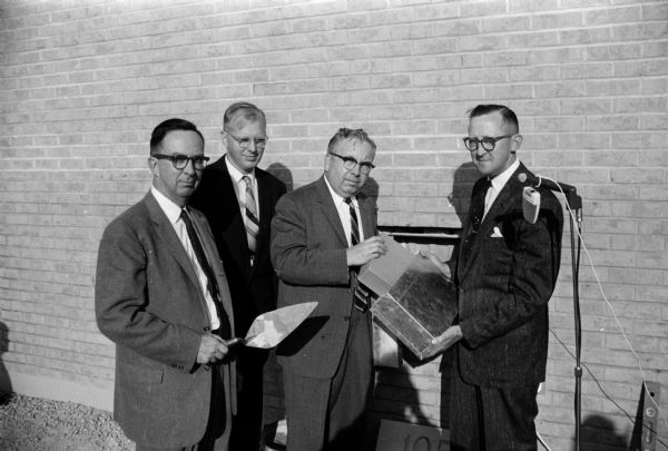 A group of men gathering to lay the cornerstone for the new Glendale Community Baptist Church at 5020 Maher. The men include, left to right: Allen Strang, architect; Rev. Perry Britton, church pastor; Rev. Ogle Chastain, Milwaukee, Chairman of Evangelism at the Wisconsin Baptist Convention and Norman Nelson, project contractor.