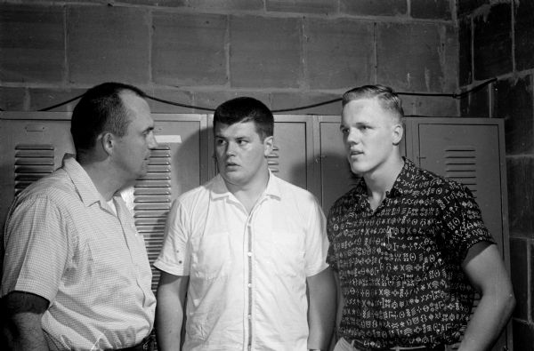 Fred Jacoby, University of Wisconsin football coaching staff, left, talks to Wisconsin freshmen football recruits. Neither had never seen a football game until entering high school. Karl Kunz of Superior, center, was born in Germany. Elmars Ezerins, Union Grove, right, is a native of Latvia.