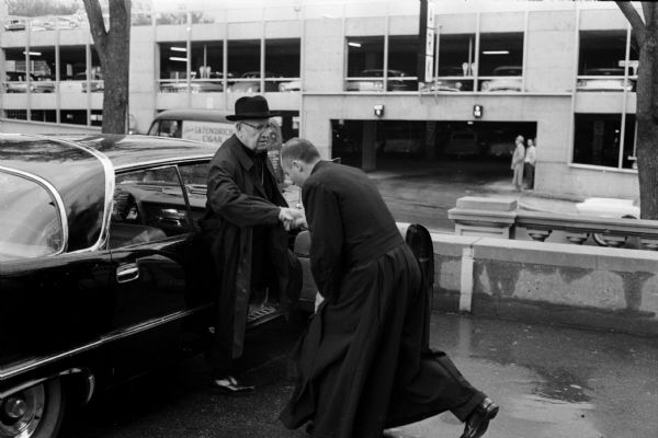 A priest genuflects while welcoming Bishop O'Connor back to Madison from his European trip. The bishop traveled in a 100 car motorcade from the railroad station to the cathedral.
