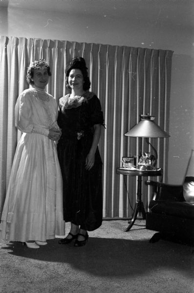 The St. Dennis Altar Society holds its second annual mother-daughter banquet. A bridal gown revue showing wedding gown styles from 1889 to the present is presented. Shown modeling two of the gowns are, left to right: Mrs. John J. Cefalu and Mrs. John O. Kohls.