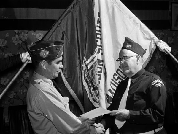 C.H. Beebe, executive director of the Madison Scouts drum and bugle corps, accepts awards won by the corps at the VFW national convention in Los Angeles, California. William Rogers, commander of Marion Canfield Post 1318 of the VFW, presents the awards.