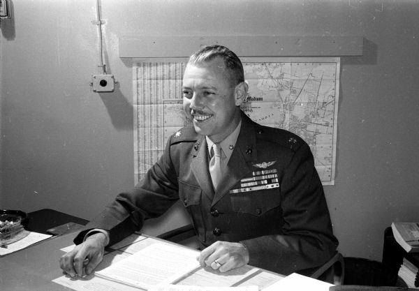 Marine Corps reserve unit adviser, Major E.G. Usher, is shown at his desk. Usher was in the news because he advised a change from a separate effort to help underprivileged children at Christmas time to a joint effort with the <i>Wisconsin State Journal's</i> annual Empty Stocking Club drive.