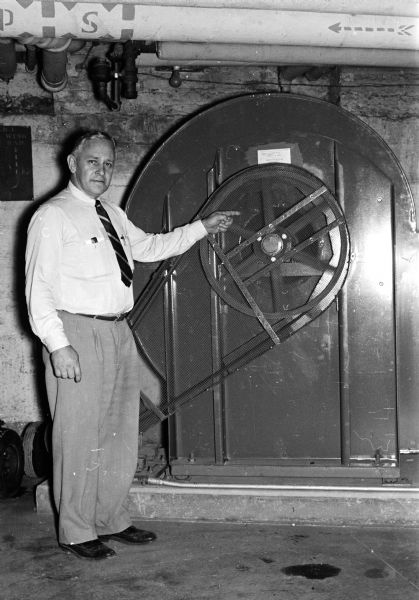 Leon A. Hendrickson, supervisor of services, pointing to a blower which is used to send air into the tunnel carrying power lines from the state power plant to the Capitol building.