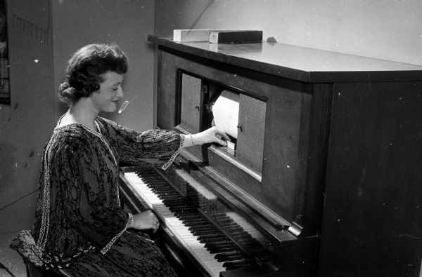 Eileen Ryan, a secretary of the Wisconsin State Historical Society, is shown looking over the player piano given to the society by Berniece LaFlash. The society had been searching for a suitable piano for over a month.