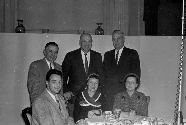The board of directors of the University of Wisconsin Alumni Club of Madison completes plans to sponsor an Alumni Rose Bowl Tour to the Pacific coast. Seated in front are: Gary Messner, Mrs. John J. Walsh, and Anya Castle. Standing left to right: Ralph Timmons, Arthur Mansfield, and Ray Sennett.