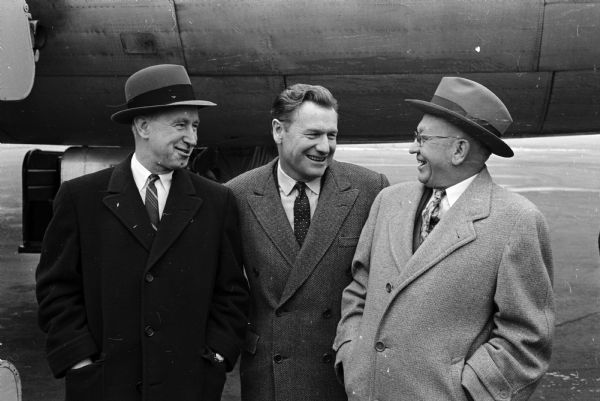 New York Governor Nelson Rockefeller is greeted by two former governors of Wisconsin at the Madison Municipal Airport. The potential presidential candidate was on a two-day tour of Wisconsin. At left is Vernon Thomson, and at right is Oscar Rennebohm.