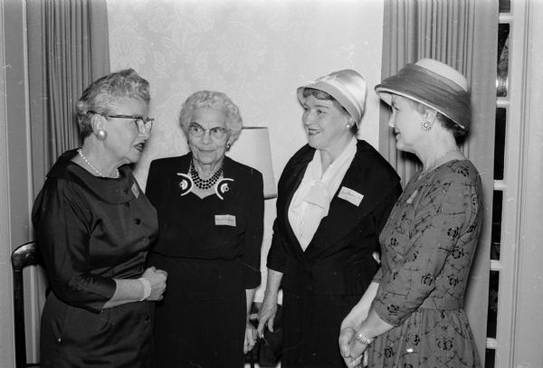 Four women chatting at the first Red Cross volunteer "thank you" tea at the home of the University of Wisconsin president. Left to right are: Mrs. Gladys Erickson, Mrs. Margaret Hibbard, Mrs. Emily Harrington, and Mrs. Iona Hein.
