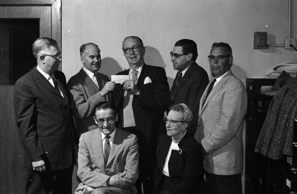Roundy's Fun Fund collected $10,362, breaking all records. Members of the Roundy's Fun Fund committee receiving the check from Roundy (Joseph L. Coughlin), are, seated in the front row: Bernard Gill, and Dagny Wang, and in the back row, left to right: Rufus Wells, James Geisler, Roundy, G.I. Wallace and Carl Waller.