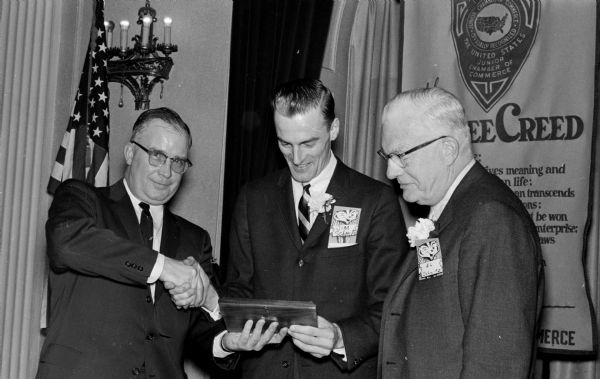 James Schmitz, center, is awarded a plaque naming him "Outstanding Young Man" of 1959 by John Shiels of the Madison Junior Chamber of Commerce. Looking on is his father, Ed Schmitz.