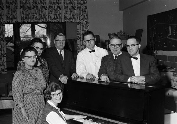 Southwest Wisconsin Council of the Telephone Pioneers of America, as their community service project, present a piano to the Children's Unit of University Hospital. Seated at the piano is Joan Goldstein, the unit's recreational director. Grouped left to right around the piano are council members Marie Vetter, Olive Graham, Orville Hankwitz; director of the unit Dr. Nathan Smith; council chairman Tom Fiedler; and Lloyd Hughes, hospital administrator.