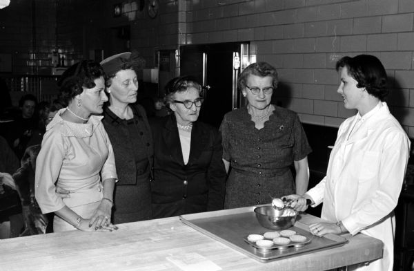 Farm and Home Week visitors look at exhibits in the University of Wisconsin home economics building. Watching a demonstration in feeding large groups are, left to right: Mrs. Lawrence Pfoff, DeForest; Mrs. Melvin Donner, Waunakee; Mrs. R.L. Paul, Perth, Australia; Mrs, George Platt, Mondovi; and Helen Rossmiller.