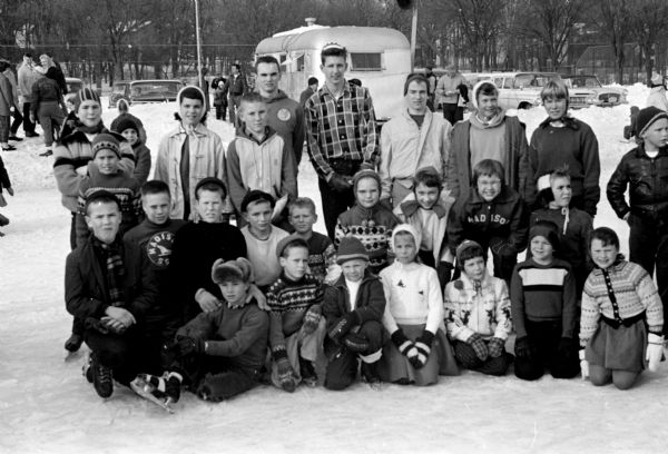 Group portrait of Madison's 1960 speed skating champions. Left to right, first row: David Singer, Freddy Davie, Jamie Thomas, Martha Lu Ferris, Jane Bush, Charles Keller, Kathleen Keeley. Second row: Dave Hall, Mike Carow, Rick Noltner, Steve Matson, John Bragg, Mary Longley, Dianne O'Neill, Betsy MacDonald, Molly Schwenn. Third row: Paul Armstrong, Jim Skelton, Gail Ploc, John Petterle, John Carrier, Don Risley, Bill Moore, Kris Thomas, Alice Jean DuBois, Chuck Mussey.