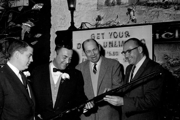 Four members of Ducks Unlimited inspect a gun at the annual banquet held at the Club Chanticleer. Left to right are: Toby Sherry, banquet chairman; Fred Gage, Tony Haen and John Lunenschloss.
