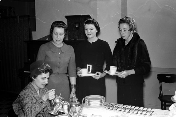 Four leaders of the Who's New Club attend their 25th anniversary tea. Left to right:  Lois Wegener (sitting at tea table); Dorothy Uehling, Dorothy Smith, and Martha Nordstrom.