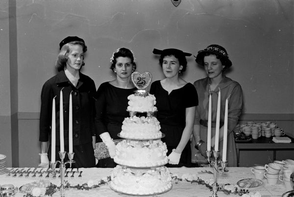 Members of the Who's New Anniversary club admire a four-tiered cake at their 25th anniversary tea. Left to right: Bonnie Tennant, Mary Waddell, Beatrice Thurow, and Mary McRaith.