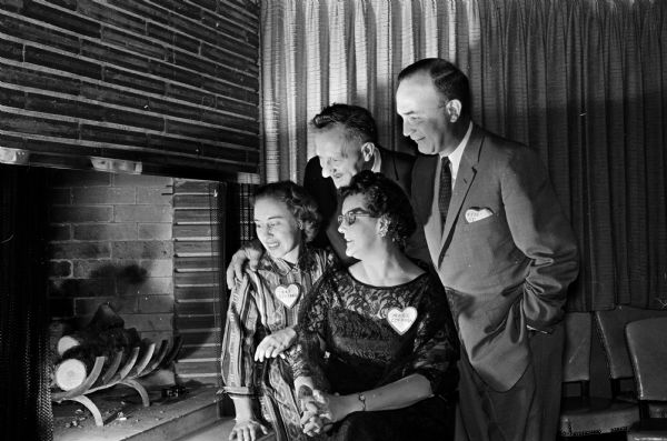 Seated or standing next to a fireplace at the Cuba Club are, left to right: Mrs. and Steve Stefani and Marie and Jerome Coffman. They are attending a dinner-dance sponsored by the Indian Hills Garden Club and are wearing Valentine name tags.