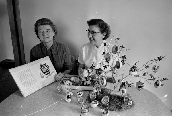 Marian Bedner (right) of Sun Prairie, who has arthritis, decorates eggs and makes egg trees for sale at the Homecrafters of Dane County 6th Annual Spring Fair. She is a student of Grace Krause, left, one of two teachers in the program for severely handicapped adults. The program is run by the Rehabilitation division of the State Board of Vocational and Adult Education.