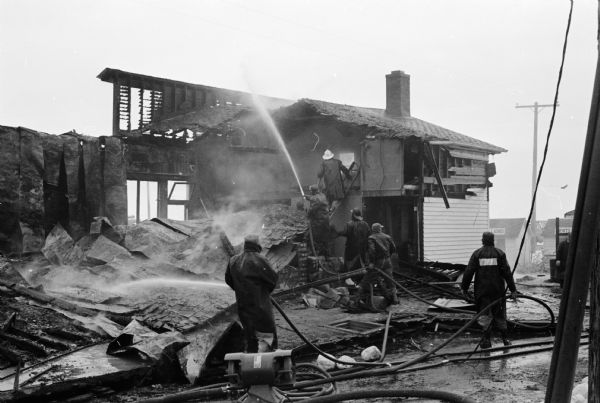 Firemen douse smoldering ruins of the Old Nora General Store on Highway 12-18 at BN and Nora Road in the Town of Cottage Grove.