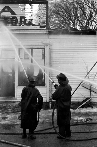 Firemen douse the smoldering ruins of the Old Nora General Store.