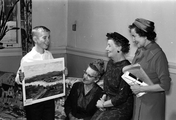 Randy Olson holds his fourth-prize winning landscape painting at the Helen Farnsworth Mears art contest for eighth graders. Admiring the painting are three of the contest judges ,left to right, Mrs. Marie Oakey, Mrs. Hazel Umland, and Mrs. D.J. Leigh.