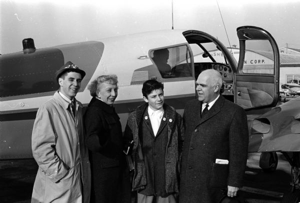 Group portrait of Mrs. Hubert Humphrey at the Madison airport with her son Hubert, Jr. (left), Sam Rizzo, Jr., son of the Humphrey campaign chairman in Wisconsin, and Philleo Nash, Wisconsin's lieutenant-governor.