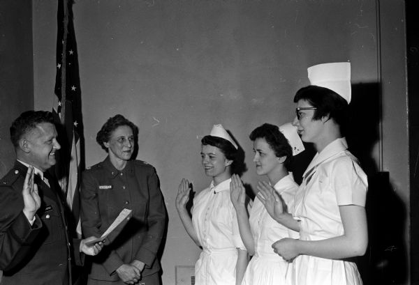 Three nurses from University Hospitals are appointed lieutenants in the Army Nurse Corps Reserve. Major Duane F. Alexander, unit adviser from the 44th General Hospital reserve unit at the hospital, administered the oath of office as Lieutenant Colonel Lola Reddeman, chief nurse, observed the ceremony. Left to right are: Rita M. Flesher, 2111 University Avenue and Marlys A. Hug and Agnes A. Moore, both of 2216 Regent Street, Madison.
