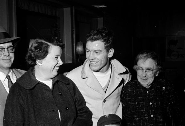 George Byrne, center, a Wisconsin State Journal carrier in Brooklyn, arrives at the airport after a twelve day trip to New York, Paris, and London. He won the trip by selling the most subscriptions to Madison newspapers. At left is his mother, Mrs. Cletus Byrne, and right, Mary Farnsworth.