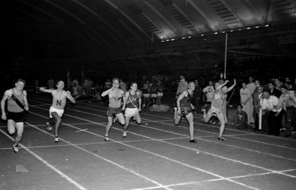 Action shot of the finish of the 60-yard dash at the West Relays at Camp Randall Memorial Stadium. Dick Berens of Madison Central High School, left, finished first and Mike Ryan of Monona Grove High School, right, was second. Rodney Putnam of Madison West High School, third from left, was fourth.