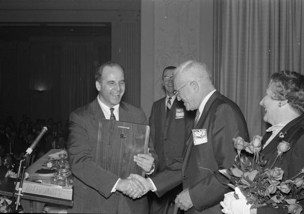 Charles W. Tomlinson (center) receives the first annual A. Jack Nussbaum Wisconsin Life Insurance Man Award from Gov. Gaylord Nelson (left). The woman with flowers is not identified.