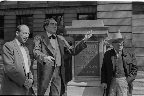 A statue of P.T. Barnum was in front of the Wisconsin State Historical Society building to announce the coming of the "Barnum Sideshow of the 19th Century" to the Circus World Museum at Baraboo. Leslie H. Fishel, Jr., left, director of the Wisconsin State Historical Society, and Joseph Mercedes, owner-operator of the side show, flank the statue. A two-horse carriage paraded the statue around the Capitol Square.
