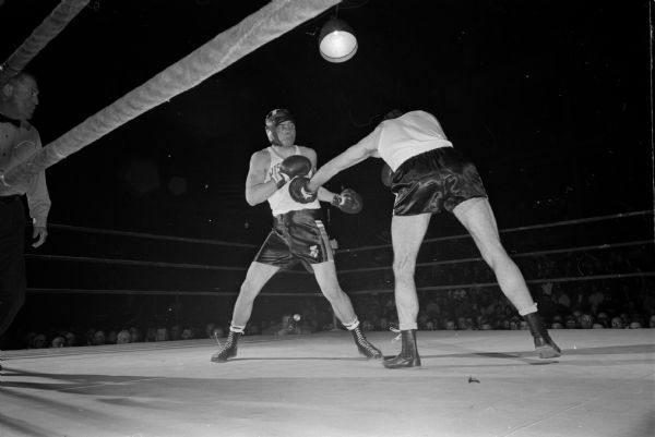 Wisconsin's Bob Christopherson (left) and Ed Fletcher of Colorado College participate in their Thursday bout during the NCAA boxing tournament at the University of Wisconsin field house. Christopherson won by a TKO to advance to the semi-final round Friday.