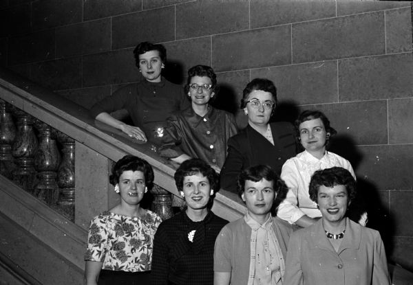 Group portrait of Madison Junior Chamber of Commerce auxiliary members who are taking leading roles in arrangements for the upcoming state convention. Bottom row, left to right: Betty Stokley, Mrs. B.D. Craig, Jacquelyn Goll, and Mary Noltner. Standing on the stairs are Rosemarie Mac Lachlan, Caryle Browne, Joe Ann Prochaska, and Marjorie Matthews.