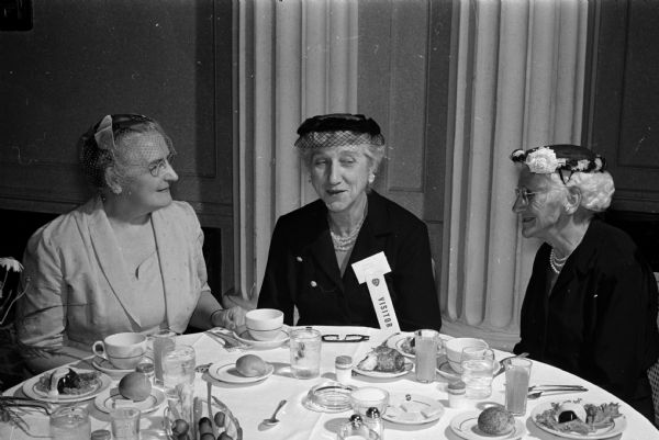 Two Madison women are joined by a state friend for the dinner program of the Wisconsin Federation of Women's Clubs. Left to right: Marie Dhein, Abigail Rundell, and Mrs. James Harris (Mineral Point). The event was held at the Loraine Hotel.