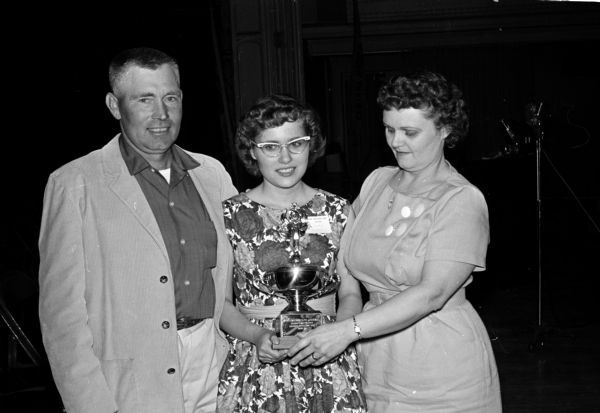 Wisconsin's 1960 spelling champion, Judy Ann Nichols, of rural Sharon, posing with her parents at the Badger Spelling Bee. Her parents, who will accompany her to Washington, D.C., for the national contest, are Mr. and Mrs. Lawrence Nichols.