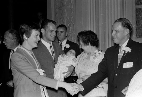 University President and Mrs. Conrad Elvehjem greet Mrs. and Mr. James Cietlow of Norwalk while their 2-month-old daughter, Ruth Ann, lies in her father's arms. They are at a reception at Great Hall.