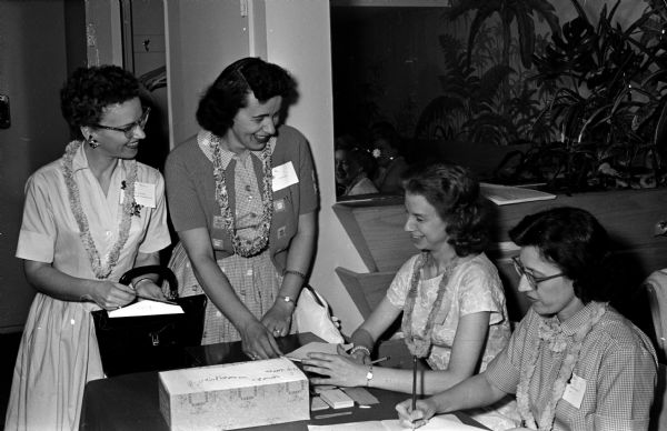 Among the registrants at the Beta Sigma Phi convention were Jean Burgess, Kansas City, Missouri, and Trude Skat (standing left), Milwaukee. They are receiving information from Betty Herritz and Norma Putman (seated at right).