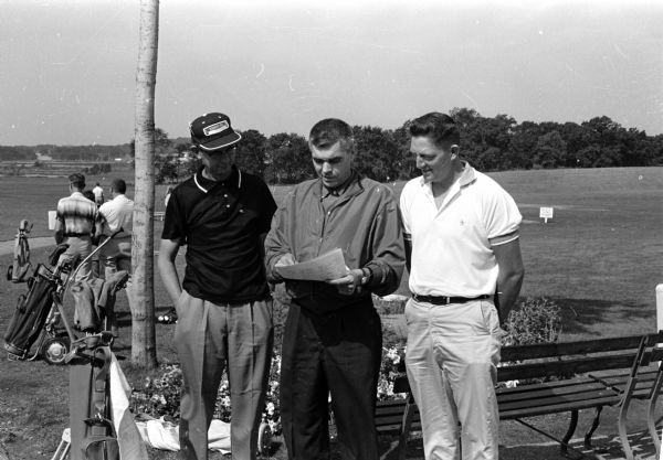 Score sheets for the 1960 City Public Golf Links Tournament at the West Side Park (Odana) are examined by, left to right, Bob Scholl, tournament co-director Rudy Ploc, and Ted Payne.