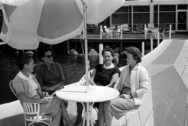 Members of the 58th annual Inland Lake Yachting Association regatta social committee discuss social events for the regatta on the Edgewater Hotel pier. Shown (left to right) are Mrs. Frank D. Bernard, Mrs. Thomas R. Hefty, Jr., Mrs. Edward H. Rikkers, and Mrs. Rodney Stebbins.