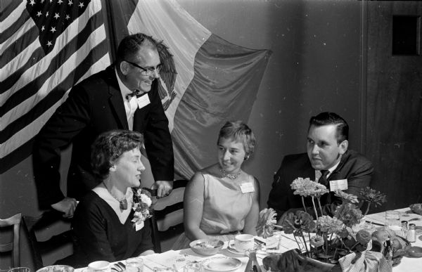 People from Mexico and their Madison area friends gather at the Truax Field Officer's Club to celebrate Mexico Independence Day. William Rosenbaum, a frequent visitor to Mexico, describes why he likes the country. Shown are Mr. Rosebaum and, seated from left, Mrs. William Rosenbaum, Mrs. Harry Scarborough, and Richard Amundson, Stoughton.