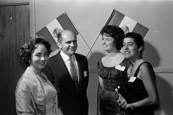People from Mexico and their Madison area friends gather at the Truax Field Officer's Club to celebrate Mexico Independence Day. Some of the Mexican women in the group are wives of men stationed at Truax Field, and some of the group are professionals working in Madison. Shown (left to right) are: Coca del Castillo, Capt. Wayne Eades, Martha Braham, and Mrs. Charles Hoffman.