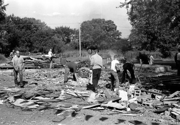 Neighbors help clean up the rubble at the site of Kellor's store and garage on Highway 14 (Oregon Road) in the Lakeview district 8 miles south of Madison. The building was demolished by a blast resulting from accumulated gasoline fumes on September 19.