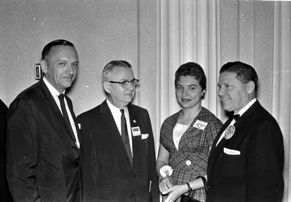 Men and women attend a breakfast in honor of the first anniversary of the Bank of Madison charge account program. They include, from left to right: Robert Heinz, publicity director of Schuster and Co. Milwaukee; Paul Schroeder, president of the Bank of Madison; Janet Foelske, employee of Mary Jane Shoes; and J. Jesse Hyman Jr., of the Emporium.