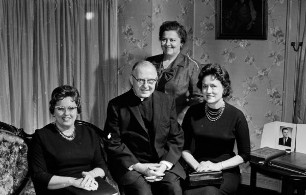 Reverend R. B. Connelly, spiritual director of the Rosary Altar Society of Blessed Sacrament Catholic Church, is shown with three of the Society officers. The women are Ruth Sweeney, second vice-president; Helen Forster (standing, president; and Betty Letendre, first vice-president. The secretary-teasurer, Katherine Lemmer, is not present.
