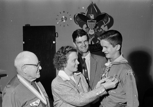 Lee Wikoff receives the badge for Eagle Scout during a Scout court of honor held at the Midvale Community Lutheran Church, Tokay Boulevard. Shown, left to right, are: Wallace S. Wikoff, father; Mrs. Wallace S. Wikoff, mother; George Morris, Dean of the Four Lakes Council of Boy Scouts; and Scout Wikoff.  
