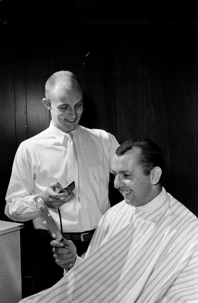 Persons attending the 34th annual state convention of the Associated Master Barbers, held at the Madison Holiday Inn, 4402 East Washington Avenue, observe a demonstration of the "free-hand crew cutting" technique also referred to as a "flat-top." Shown giving a demonstration of the technique is barber Thomas Doctor and "customer" Don Fisher, another Madison barber.