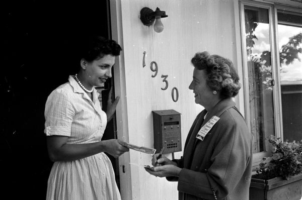 Marian Wilkie (right) makes out a receipt for a contribution to the Dane County Dollars for Democrats on the doorstep of 1930 Northwestern Avenue. Claire Dunham makes the contribution.