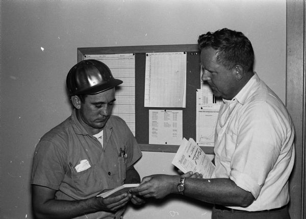Findorff Construction project foreman Paul Thering (left) receives materials and instructions for a new method of United Givers solicitation. Giving out the pledge cards is J.R. Findorff (right).