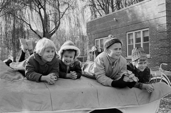 A scene from a fire school held by the Maple bluff fire department for their volunteer firemen. They witnessed demonstrations on how to put out different types of fires. Watching the firemen at work are, left to right: Mary, Jimmie, John and Ruth Weston.