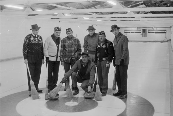 Seven members of the Madison Curling Club are ready to try out their newly polished stones and new sheets of ice. Norm Sonju is kneeling in front. Standing in back, left to right, are Gordon Harman, Bob Mortensen, Dr. John Seybold, Charles Bunn, Earl Gillette, and Jack Jerred.
