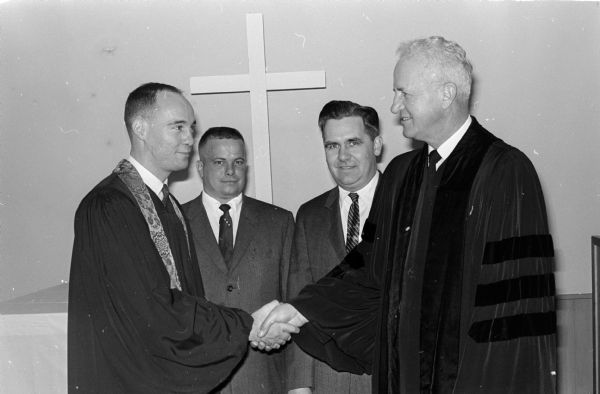 Rev. David A. Kramer (left) is congratulated by Dr. Theodore Ohlrogge (right), president of the Wisconsin District of the American Lutheran Church, after being installed as pastor of Advent Lutheran Church at its temporary location at the 7-Up Bottling Company at 5105 University Avenue. Looking on are Daniel Piquell and Robert Neiland, lay members of the congregation.